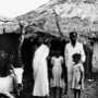 A catechist with his wife and two daughters in front of their home. The cow is a pride possession.<br />