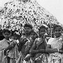 A mother with her five children standing before their home.