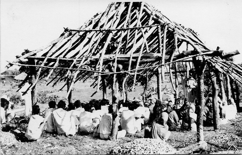 Villagers gathered in a typical 'prayer hut' which is still under construction.