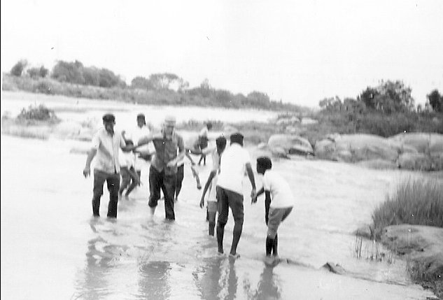 Crossing a small stream with a group of students on an outing near the college.